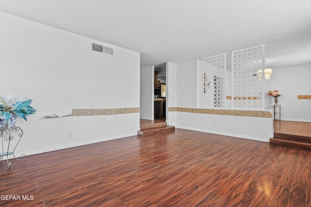 unfurnished living room with a textured ceiling and dark hardwood / wood-style flooring