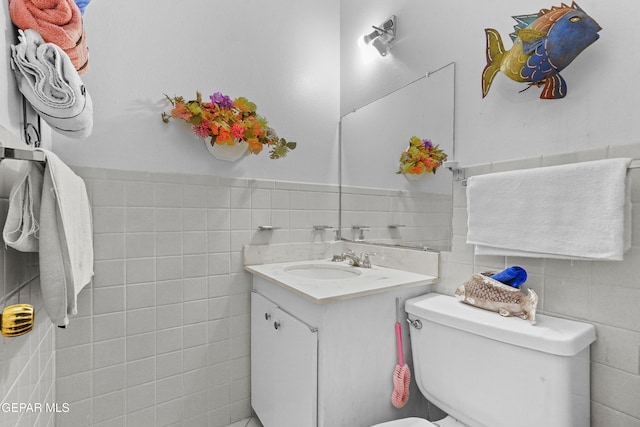 bathroom featuring toilet, tile walls, and vanity