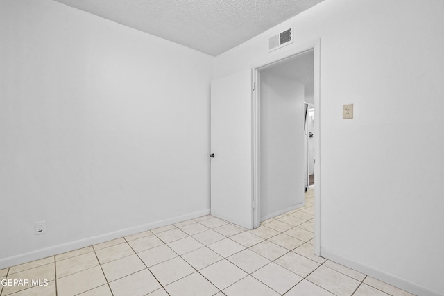 spare room with light tile patterned floors and a textured ceiling