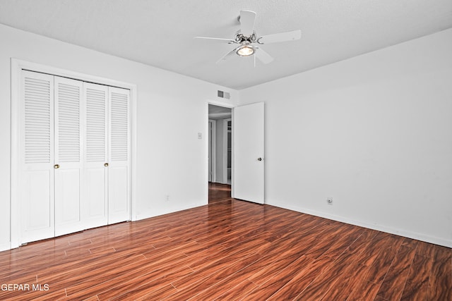 unfurnished bedroom featuring dark wood-type flooring, ceiling fan, a closet, and a textured ceiling