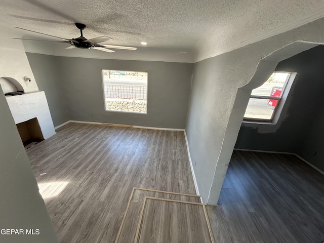 unfurnished living room with a textured ceiling, dark hardwood / wood-style flooring, and ceiling fan