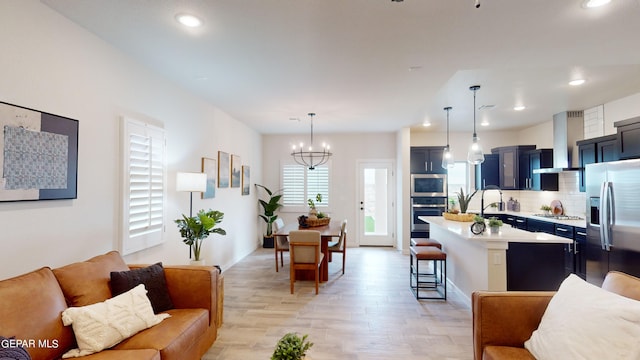 kitchen with a breakfast bar, decorative light fixtures, stainless steel appliances, light countertops, and wall chimney range hood