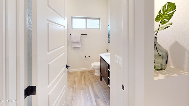 bathroom featuring wood tiled floor, baseboards, vanity, and toilet