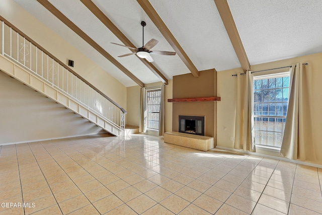 unfurnished living room featuring light tile patterned floors, ceiling fan, a fireplace, a textured ceiling, and beamed ceiling