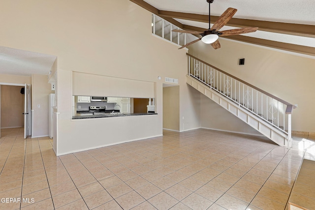 unfurnished living room featuring ceiling fan, high vaulted ceiling, beamed ceiling, and light tile patterned flooring