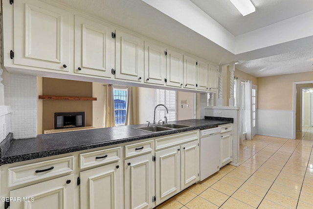 kitchen featuring light tile patterned floors, kitchen peninsula, white dishwasher, white cabinets, and sink