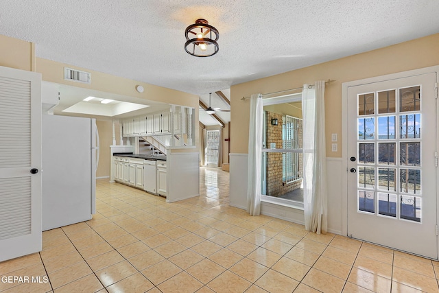 kitchen featuring ceiling fan, light tile patterned flooring, white appliances, white cabinetry, and a textured ceiling