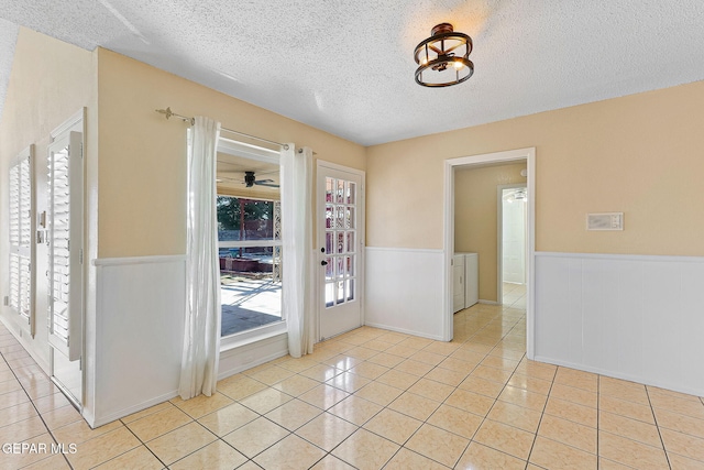 foyer featuring washing machine and dryer, light tile patterned flooring, and a textured ceiling