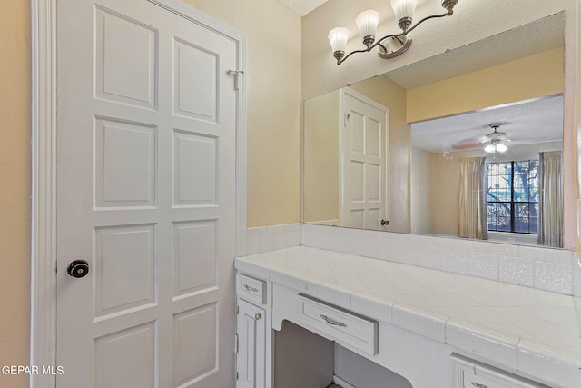 bathroom with ceiling fan, a textured ceiling, and vanity