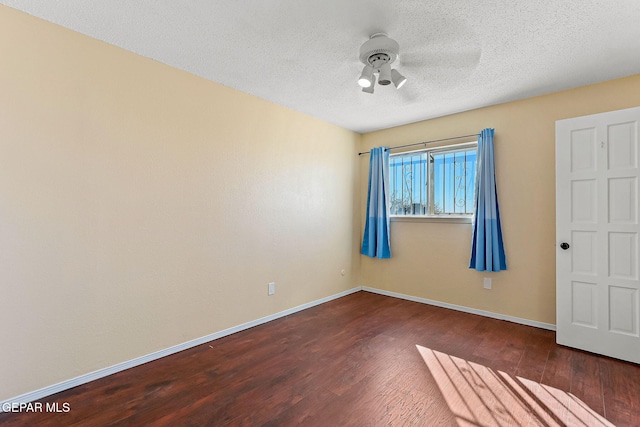 empty room with ceiling fan, dark wood-type flooring, and a textured ceiling