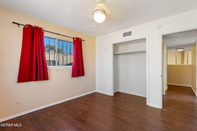 unfurnished bedroom featuring a textured ceiling, a closet, dark hardwood / wood-style floors, and ceiling fan