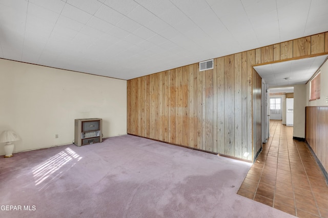 spare room featuring wooden walls and carpet flooring