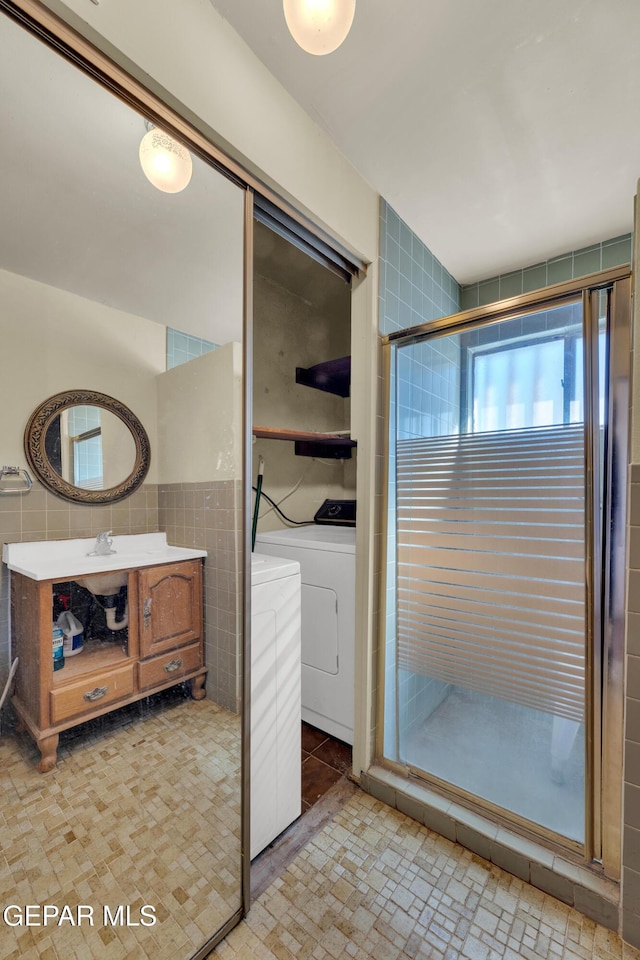 bathroom with an enclosed shower, vanity, and tile walls