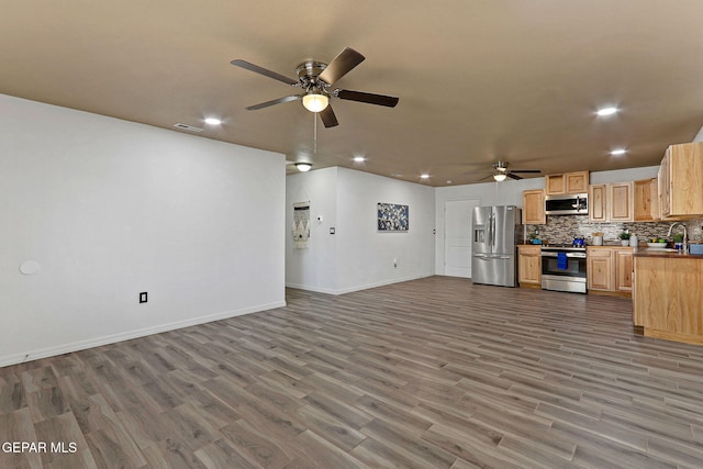 unfurnished living room with ceiling fan, hardwood / wood-style flooring, and sink