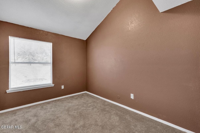 carpeted spare room featuring lofted ceiling