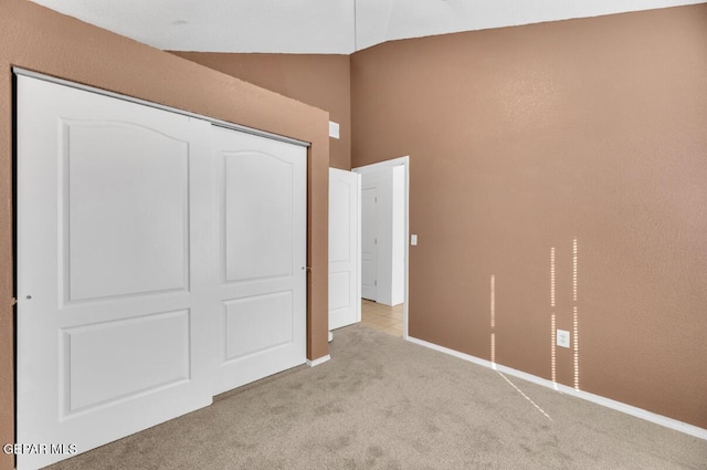 unfurnished bedroom featuring vaulted ceiling, a closet, and light carpet