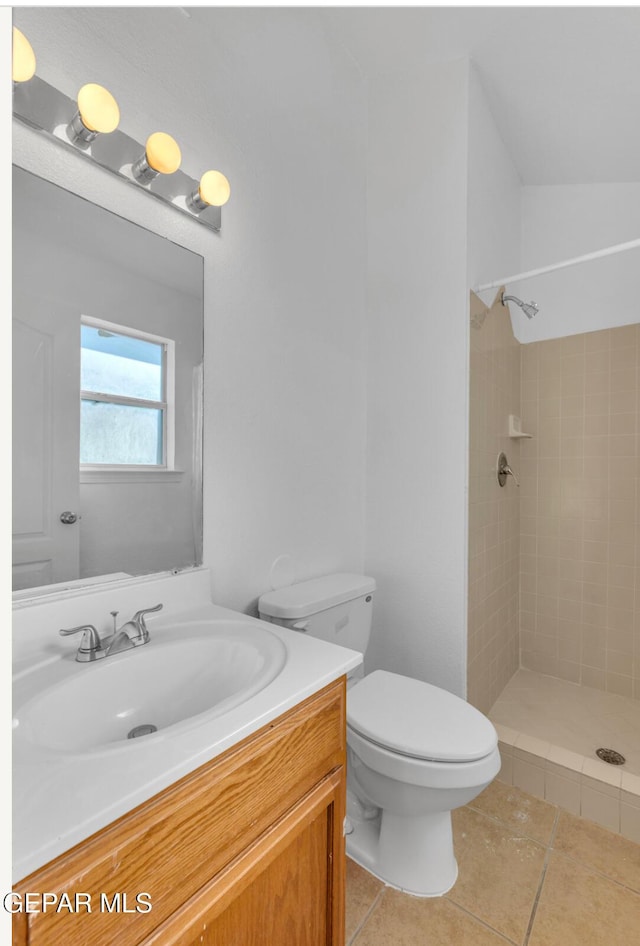 bathroom with tile patterned floors, toilet, vanity, and a tile shower