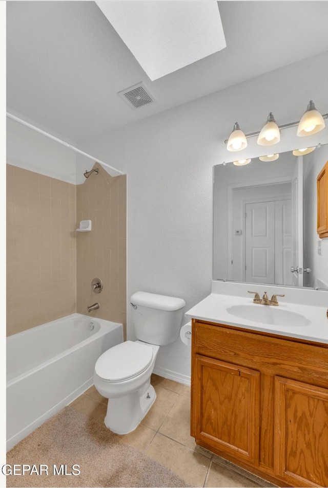 full bathroom with toilet, a skylight, tiled shower / bath combo, tile patterned floors, and vanity