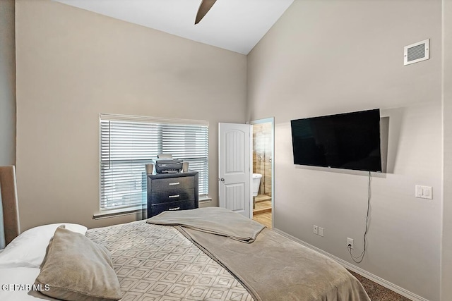 bedroom with ceiling fan, ensuite bath, light carpet, and high vaulted ceiling