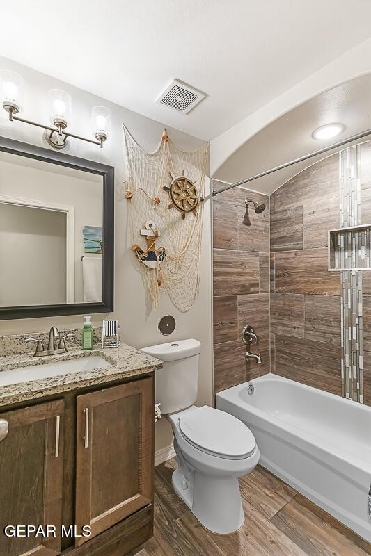 full bathroom with toilet, tiled shower / bath, and vanity