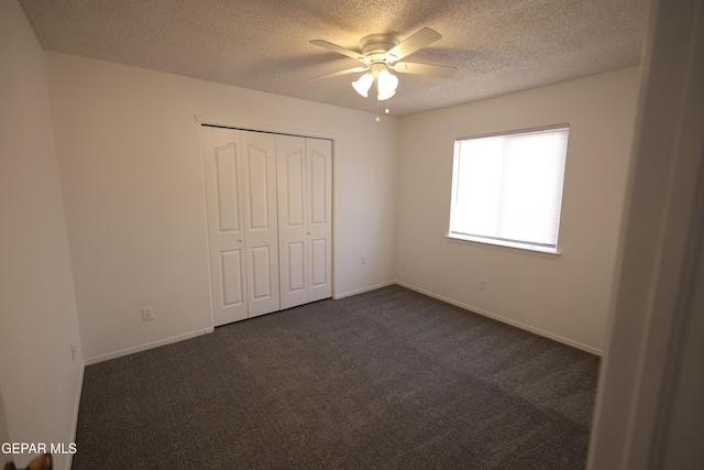 unfurnished bedroom with ceiling fan, dark carpet, a closet, and a textured ceiling