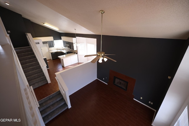 interior space with white cabinetry, dark hardwood / wood-style flooring, lofted ceiling, pendant lighting, and ceiling fan with notable chandelier