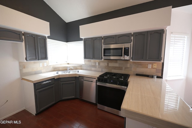 kitchen with appliances with stainless steel finishes, lofted ceiling, sink, dark hardwood / wood-style floors, and gray cabinetry