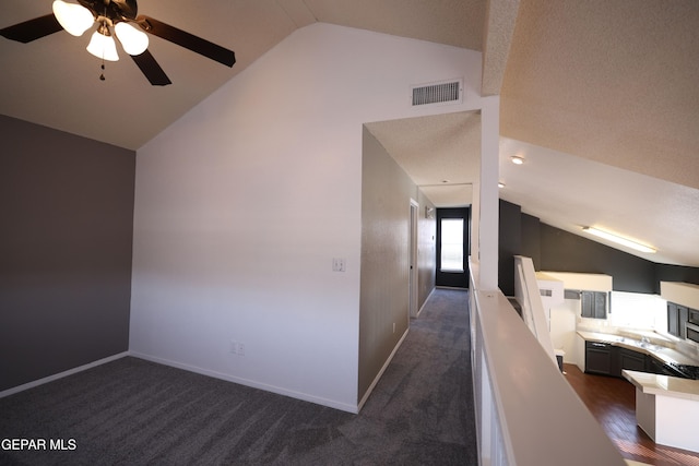 additional living space with vaulted ceiling, ceiling fan, and dark colored carpet