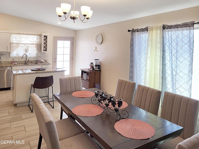 dining area with lofted ceiling, sink, and an inviting chandelier