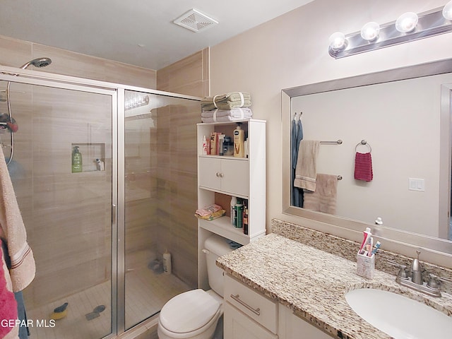 bathroom with toilet, vanity, and a shower with door