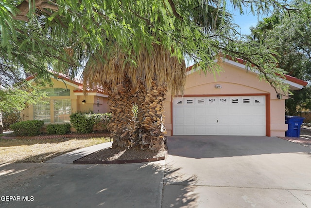 obstructed view of property with a garage, concrete driveway, and stucco siding