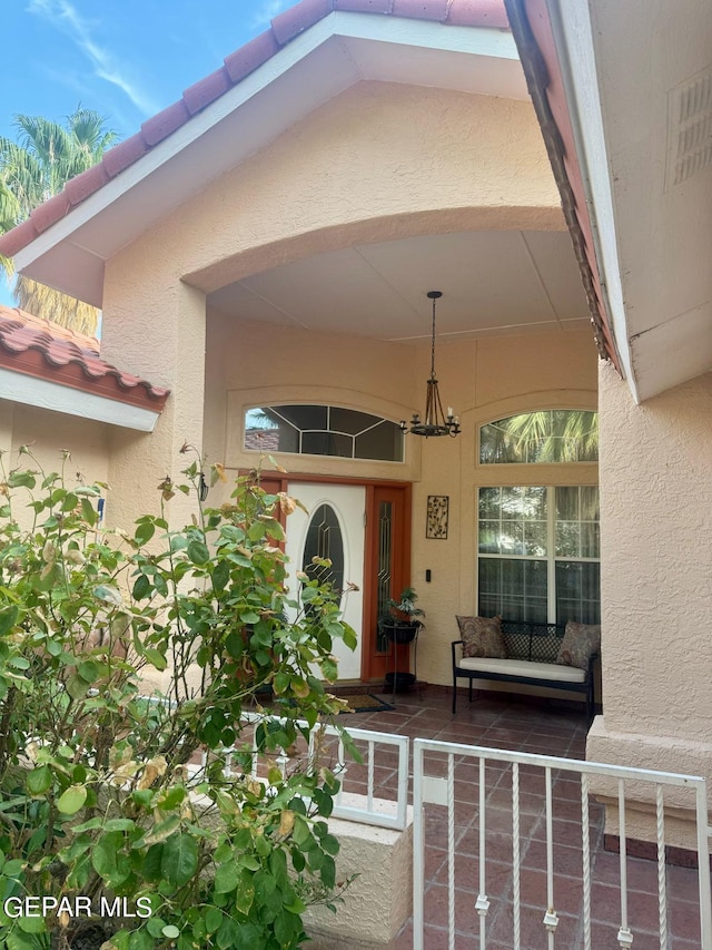 property entrance with a porch, a tile roof, and stucco siding