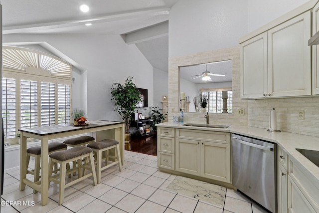 kitchen with vaulted ceiling with beams, tasteful backsplash, a sink, ceiling fan, and dishwasher