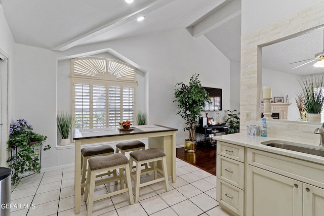 dining room featuring lofted ceiling with beams, light tile patterned floors, baseboards, and a ceiling fan