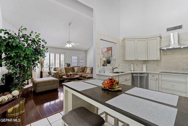 kitchen featuring high vaulted ceiling, visible vents, wall chimney range hood, dishwasher, and tasteful backsplash