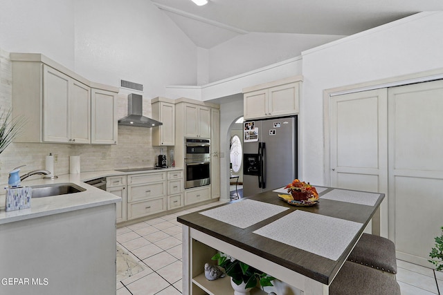 kitchen with a sink, visible vents, appliances with stainless steel finishes, wall chimney range hood, and backsplash