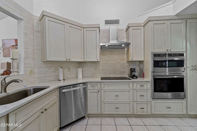 kitchen featuring stainless steel appliances, visible vents, backsplash, a sink, and wall chimney exhaust hood