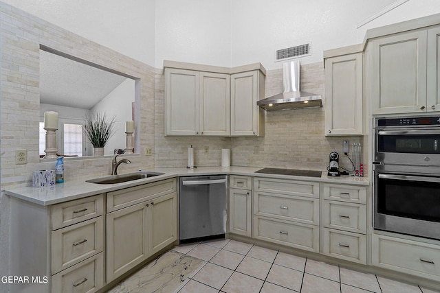 kitchen featuring light countertops, visible vents, appliances with stainless steel finishes, a sink, and wall chimney exhaust hood