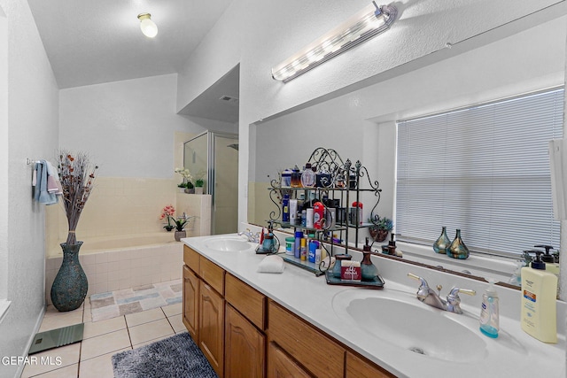 bathroom featuring a stall shower, tile patterned flooring, a garden tub, and a sink