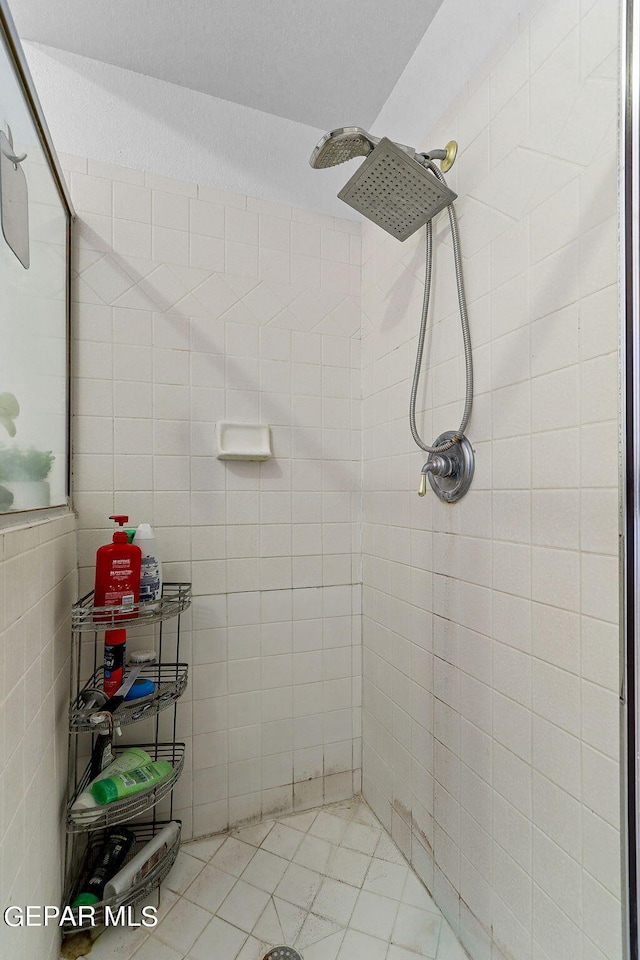 full bath with tiled shower and tile walls