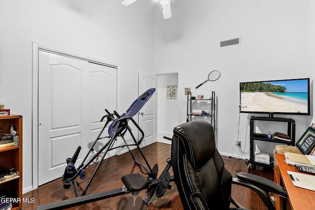 home office with visible vents, a high ceiling, a ceiling fan, wood finished floors, and baseboards