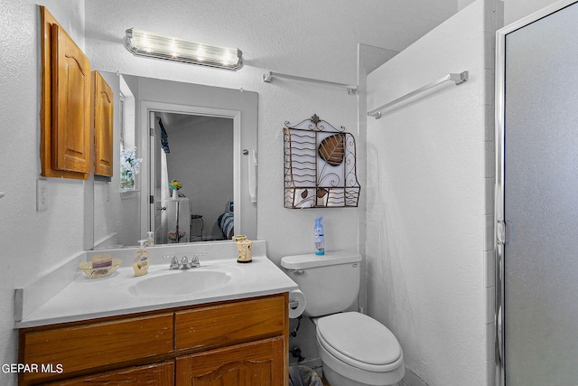 bathroom featuring a textured wall, vanity, toilet, and an enclosed shower