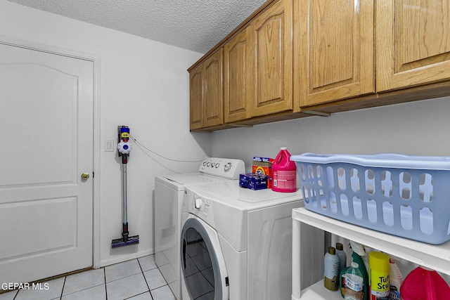 laundry room with cabinet space, washer and clothes dryer, a textured ceiling, and light tile patterned floors