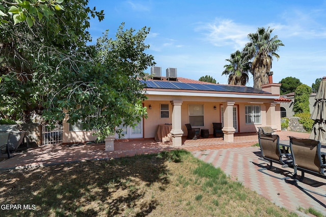 rear view of house featuring solar panels, central air condition unit, a patio, and stucco siding