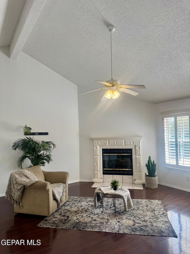 living room featuring vaulted ceiling with beams, baseboards, a tiled fireplace, and wood finished floors