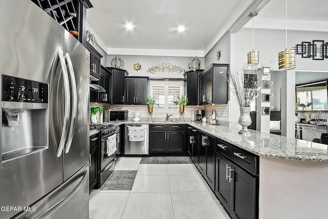 kitchen featuring backsplash, sink, hanging light fixtures, appliances with stainless steel finishes, and light stone counters