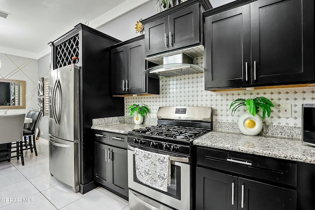 kitchen featuring light tile patterned floors, stainless steel appliances, tasteful backsplash, light stone countertops, and wall chimney exhaust hood