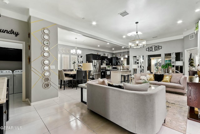 tiled living room with independent washer and dryer and an inviting chandelier