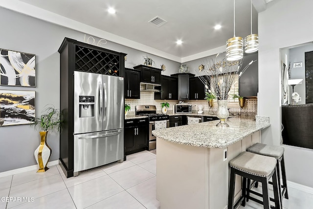 kitchen featuring a kitchen bar, kitchen peninsula, appliances with stainless steel finishes, decorative backsplash, and pendant lighting