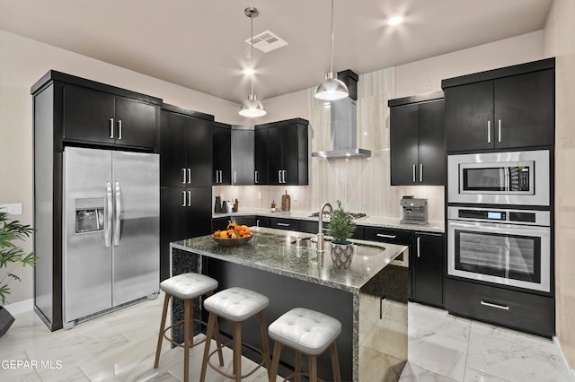 kitchen with stainless steel appliances, a kitchen island with sink, pendant lighting, a breakfast bar, and sink